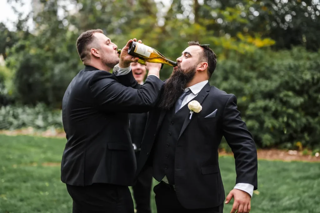 Groomsmen candidly drinking champagne in a garden