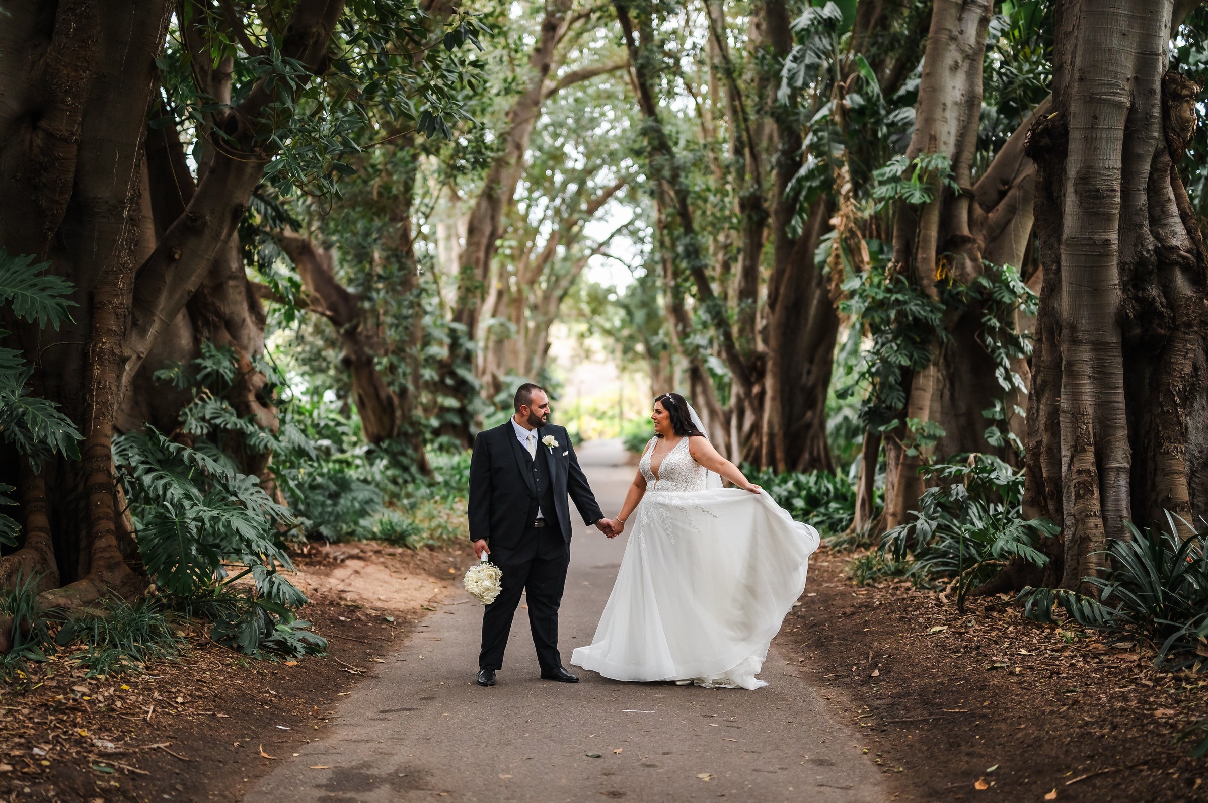 Milan and Jess holding hands on a tree-lined avenue, Adelaide wedding by Kalf Productions